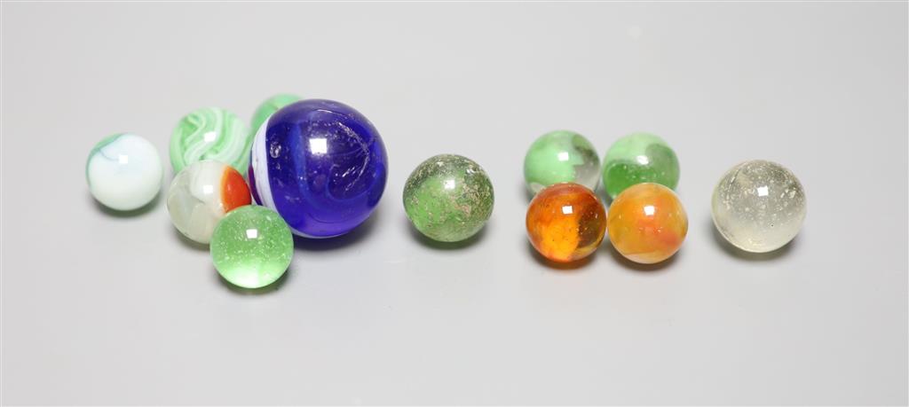 A large Victorian glass marble and eleven smaller marbles